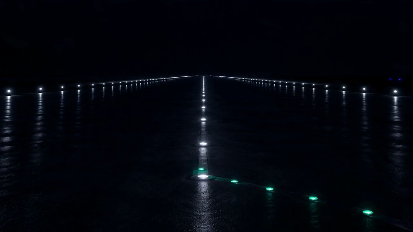 Green taxiway lead-on lights curving onto a runway centreline at night